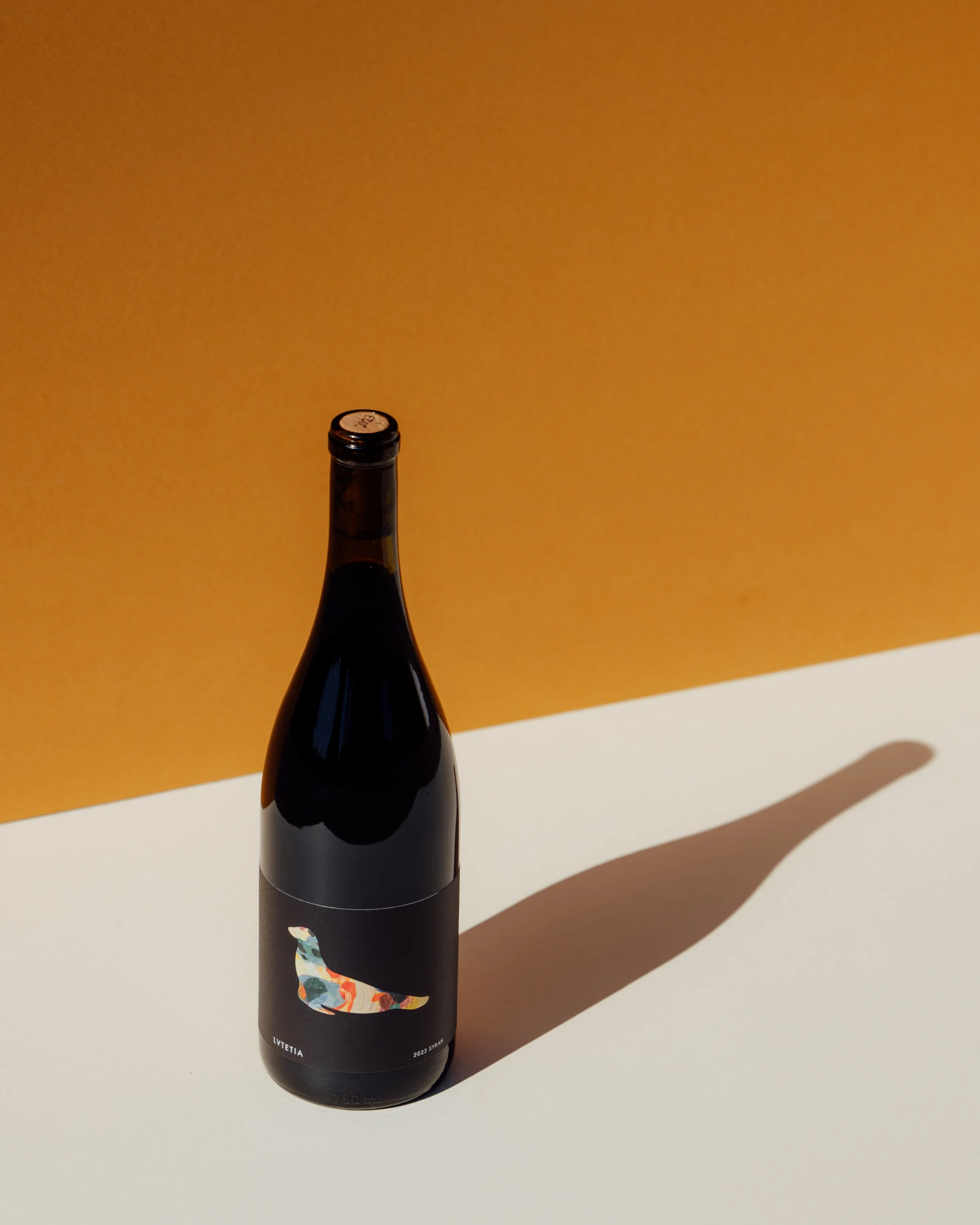 A Sealionne bottle on a golden wall, its shadow across a white table