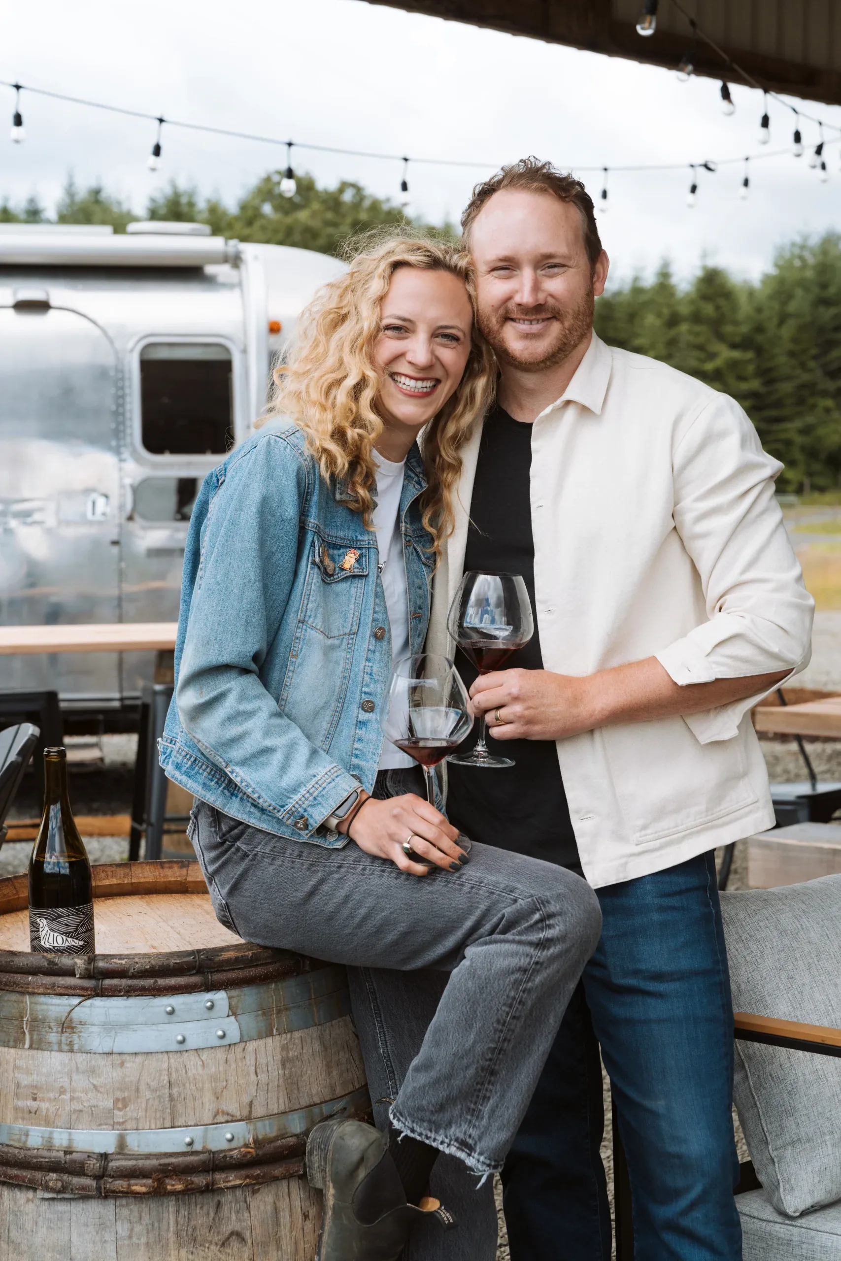 Piper Underbrink and her husband, Ben, with glasses of red wine in front of the Airstream
